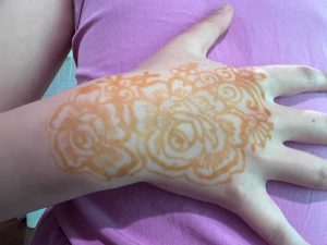 Child's hand and wrist adorned with henna flowers.