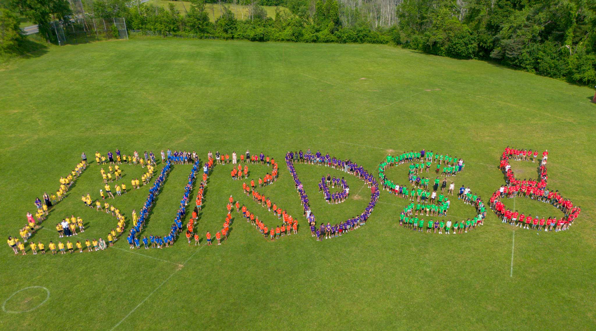 Students standing in the shape of letters for BIRDS ariel photo.