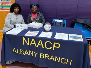 Two women sit at NAACP Albany Branch table.