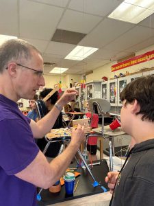 Teacher works with student on assembling a Rube Goldberg machine.