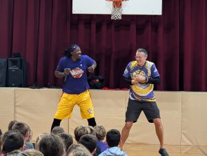 Member of the Harlem Wizards dances with an adult staff member.