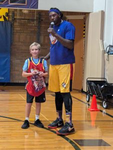 Student stands next to a member of the Harlem Wizards.