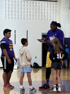 Students stands next to a member of the Harlem Wizards.