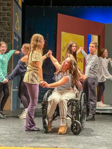 Students dancing on stage. One student is in a wheelchair.