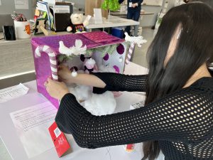 Teen creates a miniature window display of fashions with a December holiday theme.