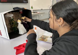 Teen creates a miniature window display of fashions with a December holiday theme.